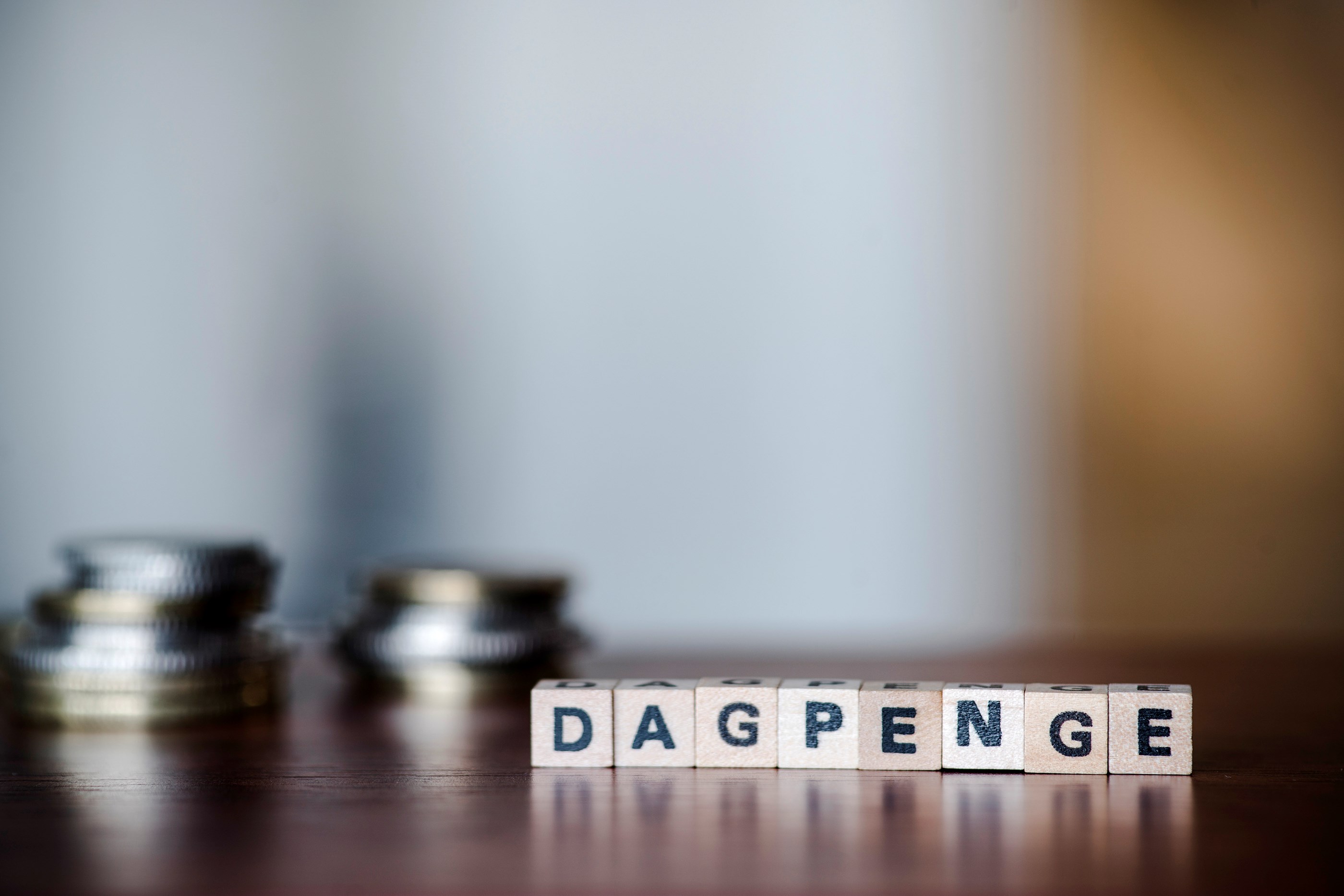 Dagpenge illustration. Træklodser på bord, hvor der står "dagpenge". 
