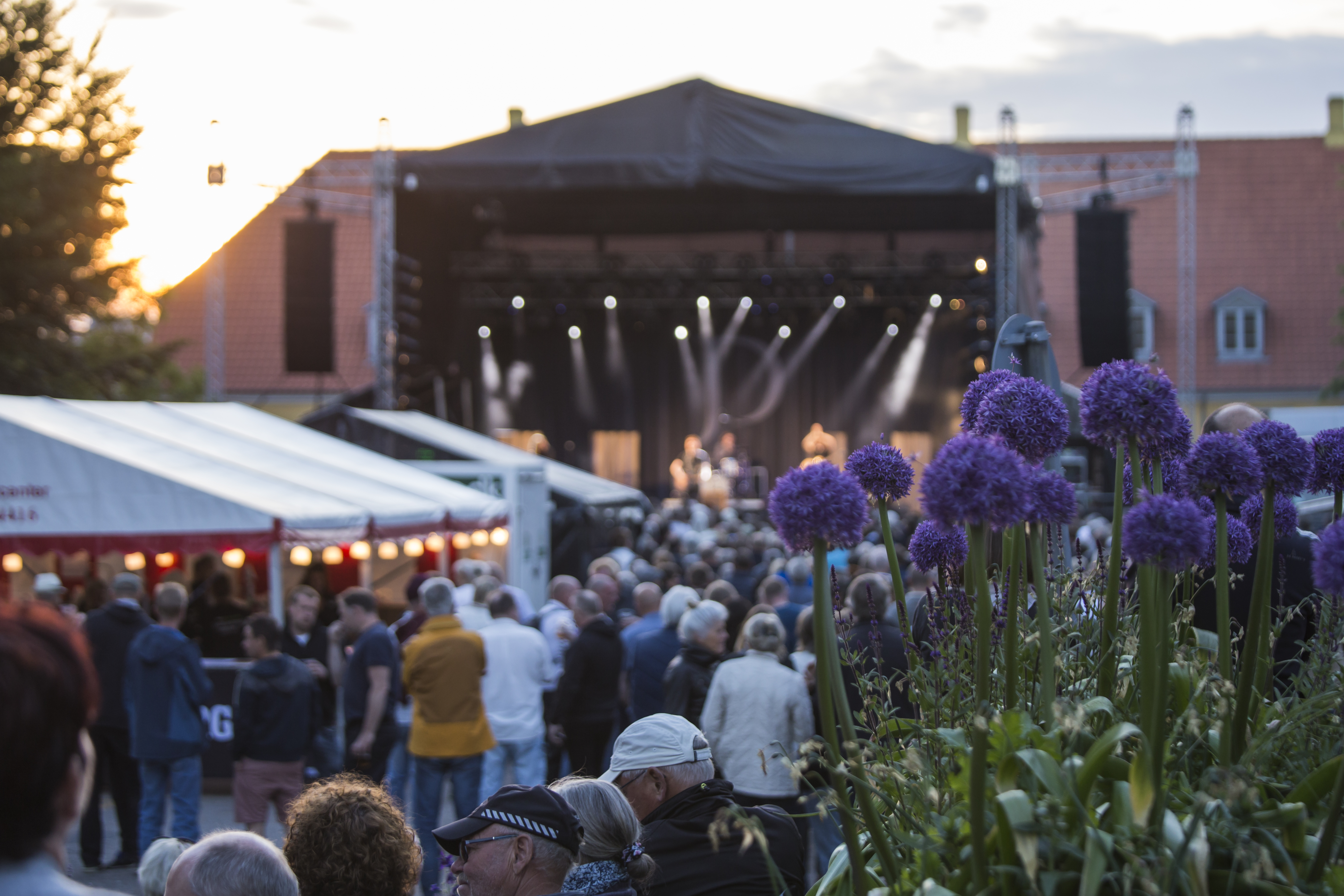 Personer foran scene med blomster i forgrunden